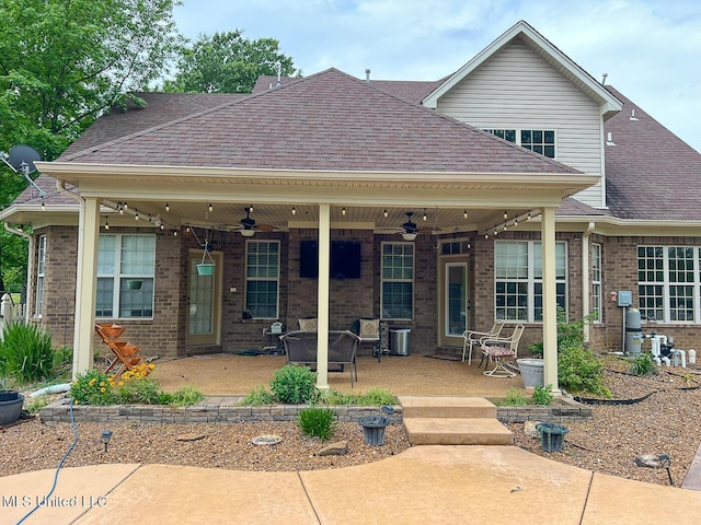 back of house featuring brick siding, a ceiling fan, and roof with shingles