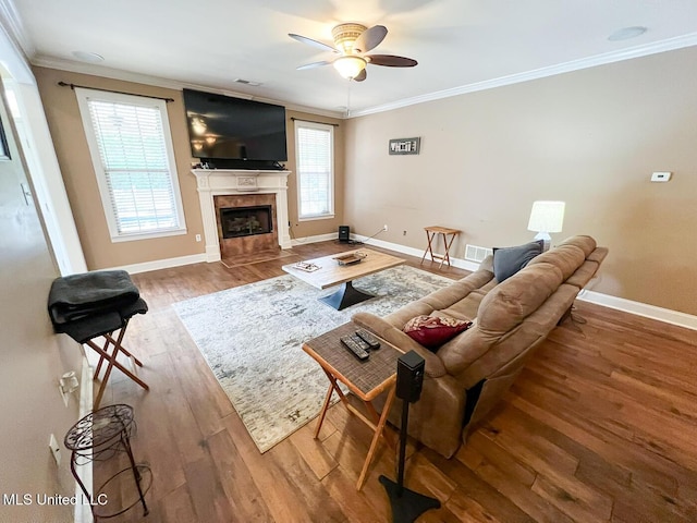 living area with crown molding, wood finished floors, baseboards, ceiling fan, and a tile fireplace