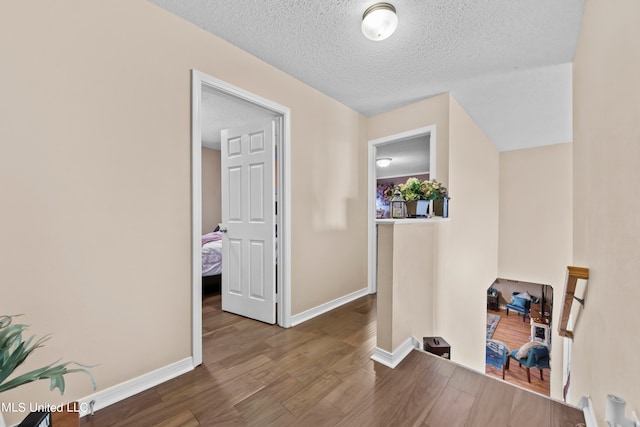 corridor with hardwood / wood-style floors and a textured ceiling