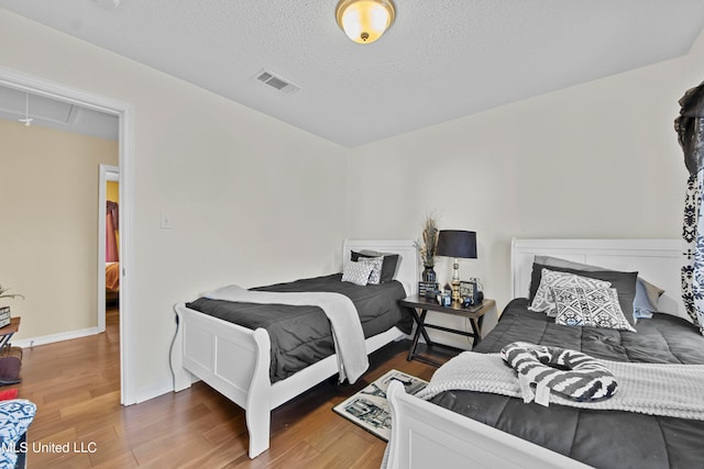 bedroom with a textured ceiling and dark hardwood / wood-style floors