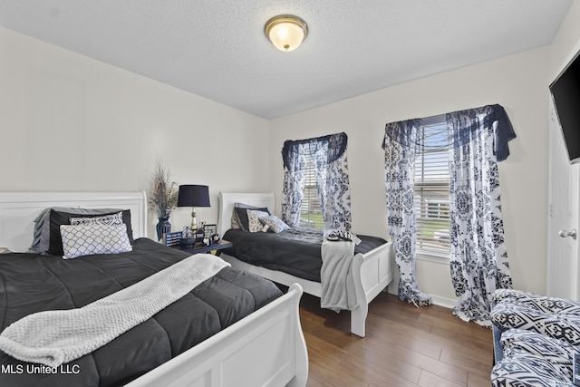 bedroom with wood finished floors, a textured ceiling, and baseboards