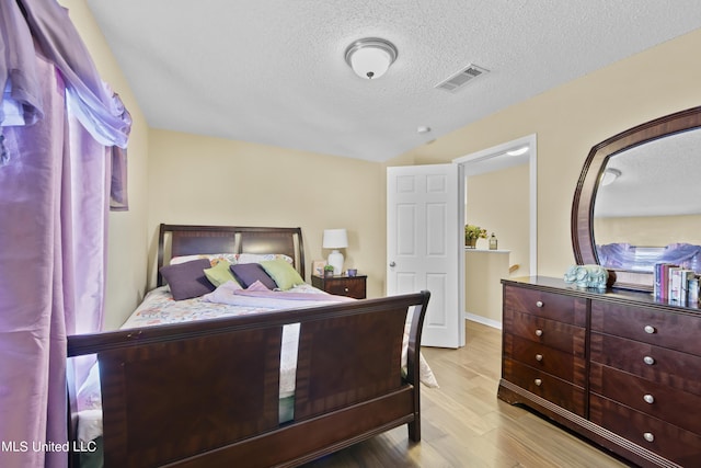 bedroom with a textured ceiling, wood finished floors, and visible vents