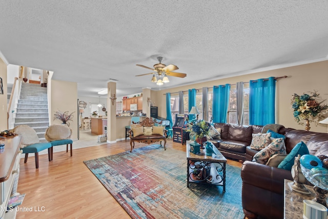 living room featuring ornamental molding, a textured ceiling, light hardwood / wood-style floors, and ceiling fan