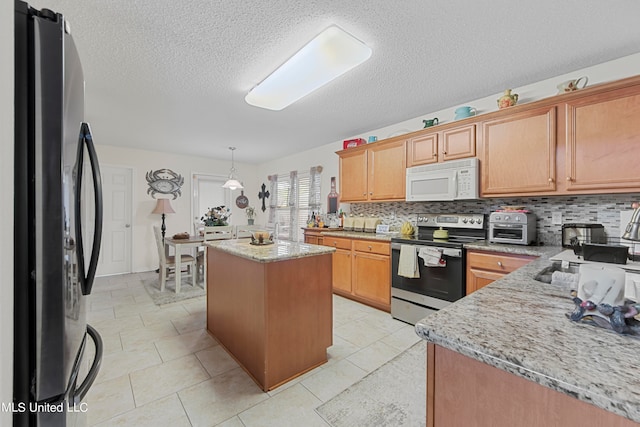 kitchen with tasteful backsplash, a kitchen island, appliances with stainless steel finishes, light stone countertops, and pendant lighting