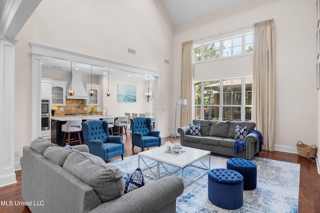 living room with a high ceiling, dark wood-type flooring, and crown molding