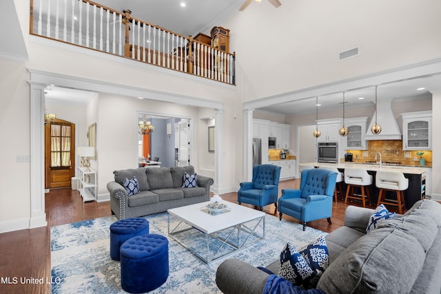 living room featuring ornate columns, crown molding, a towering ceiling, and dark hardwood / wood-style floors