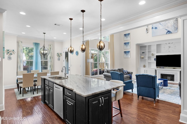 kitchen with dark hardwood / wood-style floors, sink, hanging light fixtures, and an island with sink