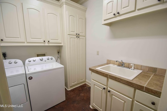 clothes washing area with cabinets, crown molding, sink, and washing machine and clothes dryer