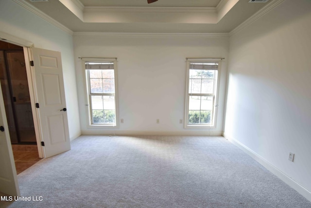 carpeted spare room featuring a wealth of natural light, crown molding, and a tray ceiling