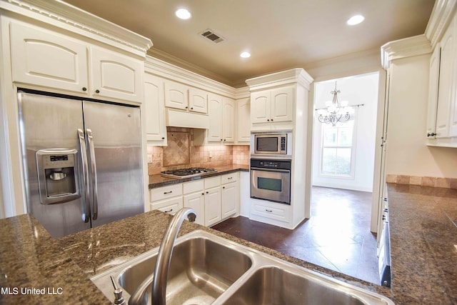 kitchen featuring a notable chandelier, appliances with stainless steel finishes, sink, and ornamental molding