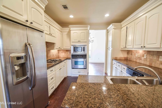 kitchen featuring white cabinets, backsplash, dark stone countertops, sink, and stainless steel appliances