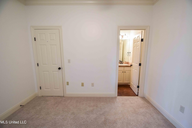 unfurnished bedroom featuring connected bathroom, crown molding, carpet flooring, and sink