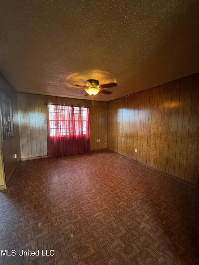 704 Oak Ave, Ruleville, MS 38771 - unfurnished room featuring a textured ceiling, ceiling fan, wood walls, and baseboards