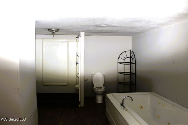 bathroom featuring a bath, a textured ceiling, toilet, and hardwood / wood-style floors