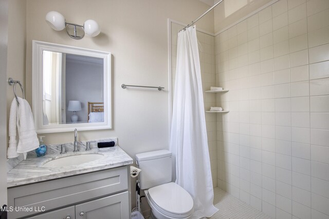 full bathroom with toilet, vanity, and tiled shower