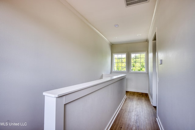 corridor featuring baseboards, visible vents, dark wood-type flooring, and ornamental molding