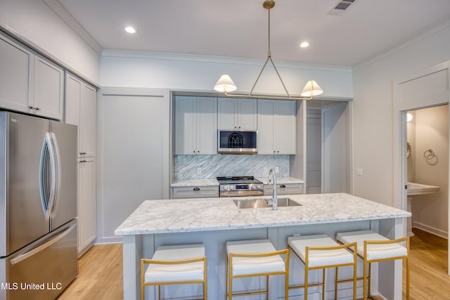 kitchen featuring a kitchen bar, a sink, backsplash, and appliances with stainless steel finishes
