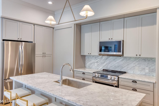 kitchen with a sink, decorative backsplash, a breakfast bar area, appliances with stainless steel finishes, and light stone countertops