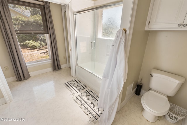 bathroom featuring a healthy amount of sunlight, bath / shower combo with glass door, toilet, and tile patterned flooring