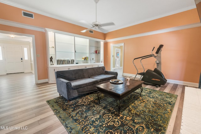 living room featuring ornamental molding, light hardwood / wood-style flooring, built in features, and ceiling fan