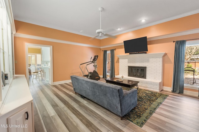 living room with light hardwood / wood-style floors, ornamental molding, a fireplace, and ceiling fan