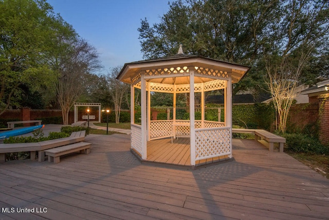 deck at dusk featuring a gazebo