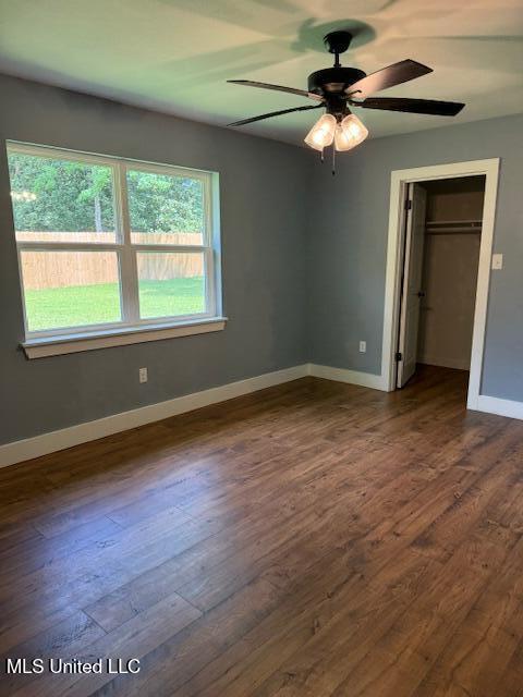 unfurnished bedroom with a closet, ceiling fan, and dark wood-type flooring