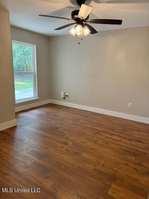 unfurnished room featuring dark wood-type flooring and ceiling fan