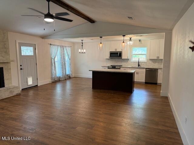 kitchen with decorative light fixtures, a fireplace, white cabinets, tasteful backsplash, and appliances with stainless steel finishes