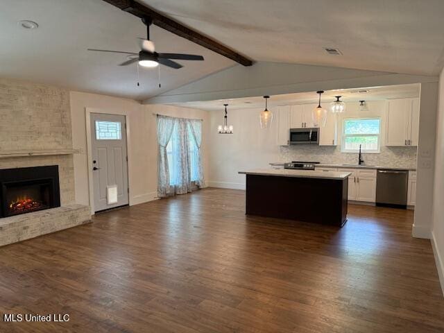 kitchen featuring stainless steel appliances, decorative light fixtures, white cabinetry, tasteful backsplash, and a kitchen island