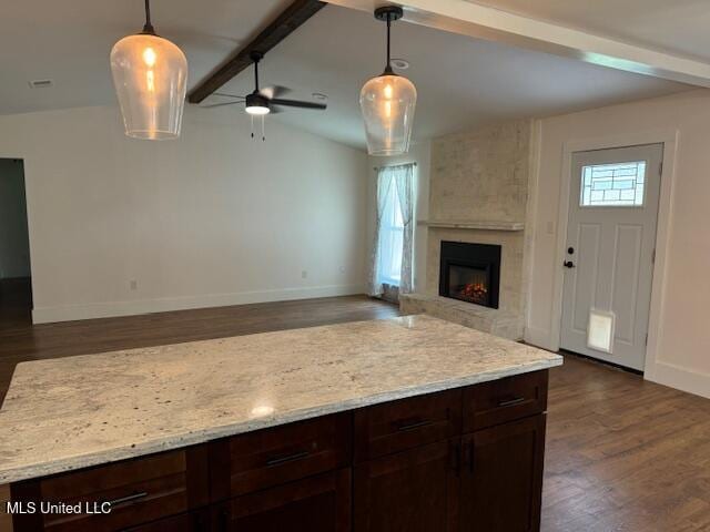 kitchen featuring a large fireplace, hanging light fixtures, and dark wood-type flooring