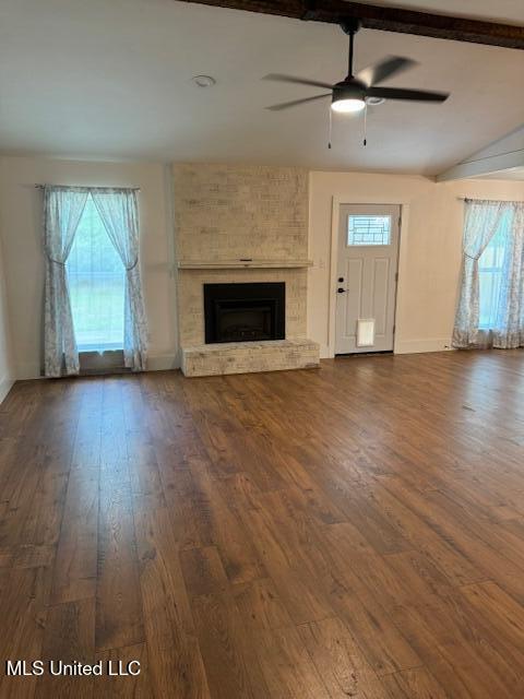 unfurnished living room with ceiling fan, dark wood-type flooring, and a large fireplace