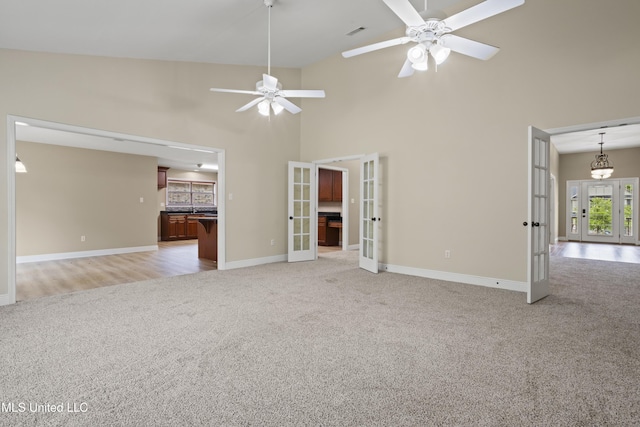 13239 Tyler Ln, Gulfport, MS 39503 - unfurnished living room with french doors, light carpet, ceiling fan, baseboards, and high vaulted ceiling