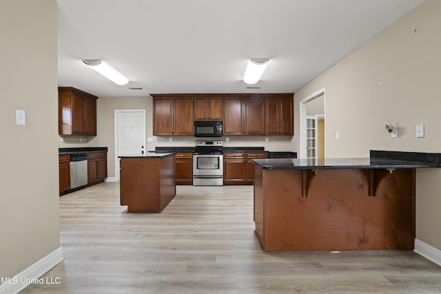 13239 Tyler Ln, Gulfport, MS 39503 - kitchen featuring stainless steel appliances, a peninsula, baseboards, light wood-style flooring, and a breakfast bar area