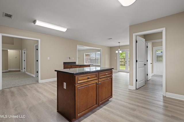 13239 Tyler Ln, Gulfport, MS 39503 - kitchen with a kitchen island, light wood finished floors, baseboards, brown cabinets, and decorative light fixtures