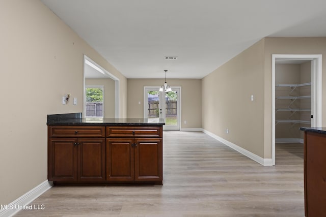 13239 Tyler Ln, Gulfport, MS 39503 - kitchen featuring light wood-style flooring, baseboards, dark stone counters, and hanging light fixtures