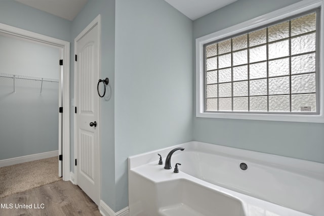 13239 Tyler Ln, Gulfport, MS 39503 - full bathroom featuring a bath, wood finished floors, baseboards, and a walk in closet