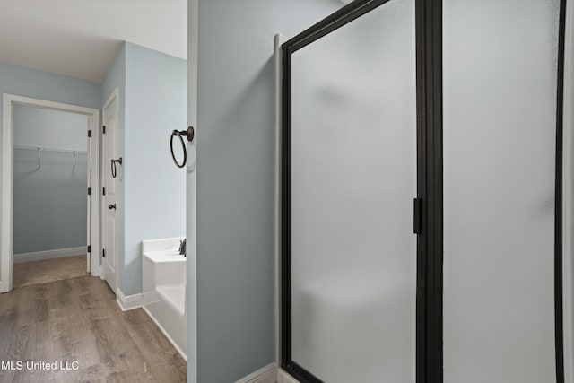 13239 Tyler Ln, Gulfport, MS 39503 - bathroom with a bath, wood finished floors, a spacious closet, and a shower stall