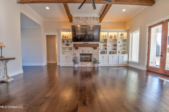 unfurnished living room with beamed ceiling, a brick fireplace, ornamental molding, and dark wood-type flooring