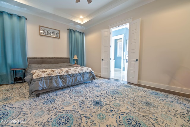 bedroom featuring ceiling fan, a tray ceiling, and ornamental molding