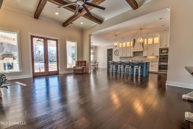 living room featuring dark hardwood / wood-style flooring, french doors, beamed ceiling, sink, and ceiling fan