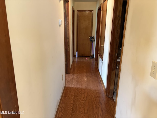 corridor featuring baseboards and wood finished floors