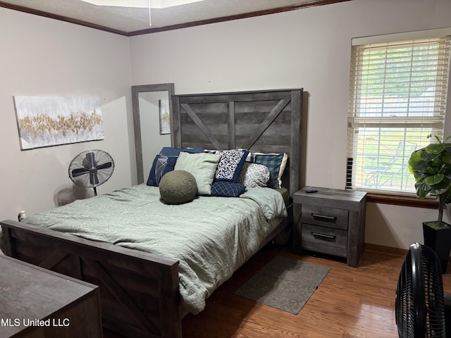 bedroom featuring crown molding, baseboards, multiple windows, and wood finished floors