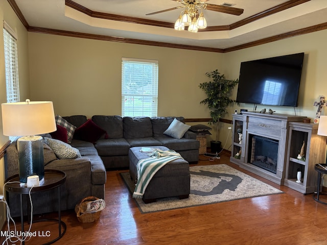 living area with crown molding, plenty of natural light, a tray ceiling, and ceiling fan