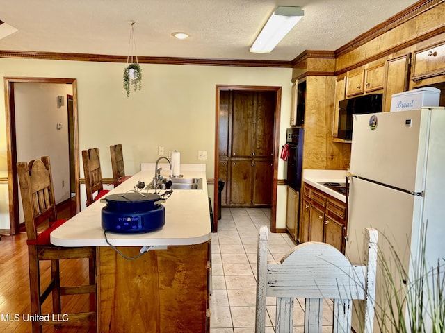 kitchen with a sink, light countertops, freestanding refrigerator, electric cooktop, and oven