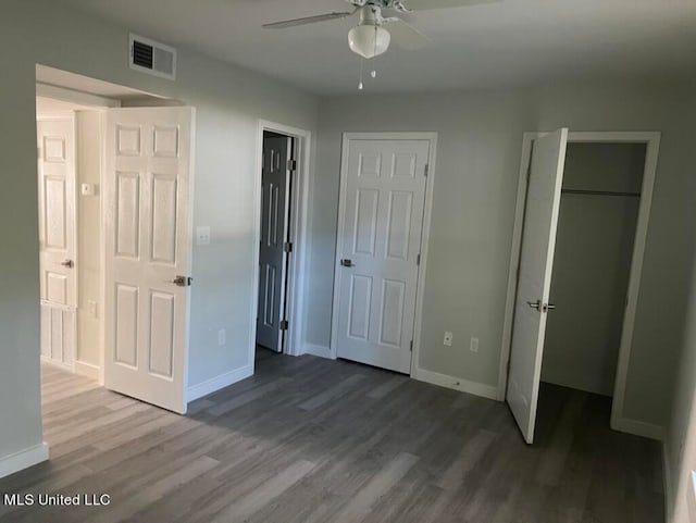 unfurnished bedroom with two closets, wood-type flooring, and ceiling fan