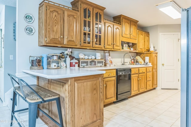 kitchen featuring black dishwasher, light countertops, a breakfast bar, glass insert cabinets, and a sink