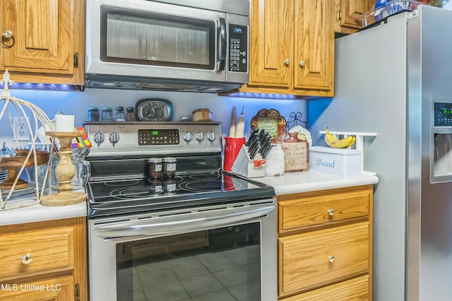 kitchen with appliances with stainless steel finishes, light countertops, tile patterned flooring, and brown cabinets