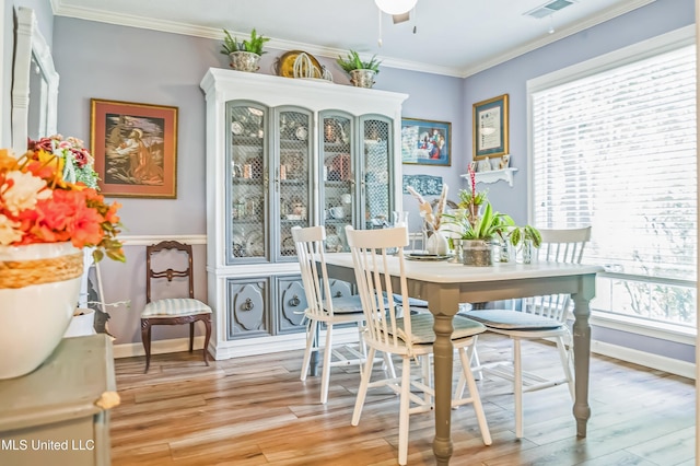 dining room with light wood-type flooring, ornamental molding, and baseboards