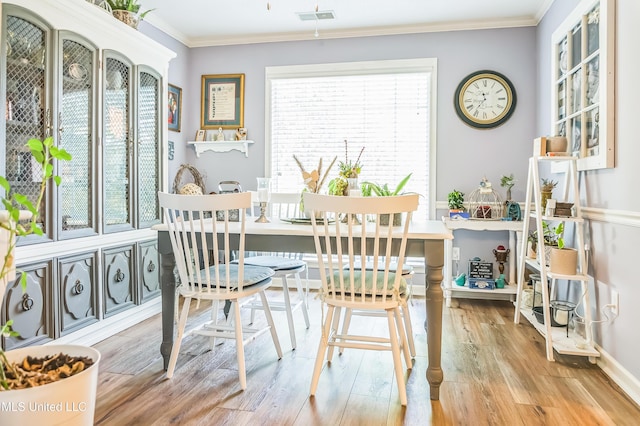 dining room with wood finished floors, crown molding, and baseboards